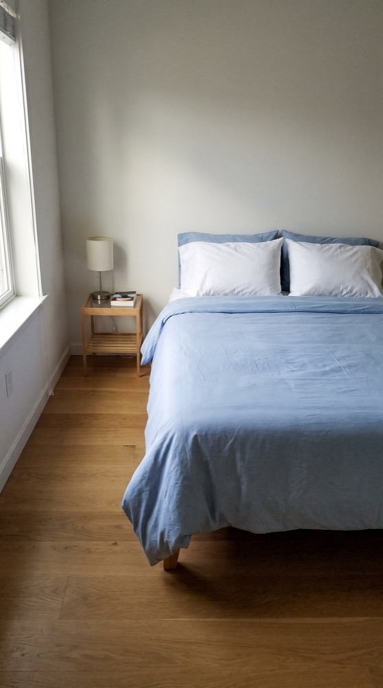 The same bedroom after cleaning, neatly made bed